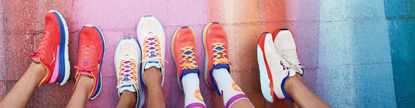 Men and women on rainbow wall wearing Hoka Start Pack running collection