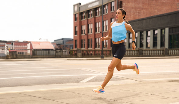 A man and a woman running on a sidewalk in HOKA Mach 5 running shoes.