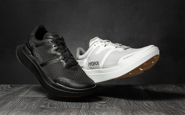 a person standing on a city curb in HOKA Transport X black and white unisex running shoes