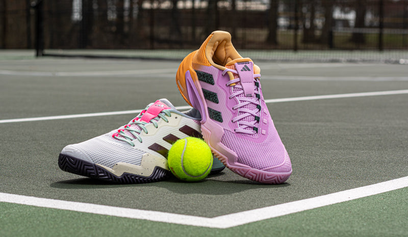 adidas barricade tennis shoes on tennis court with teniss ball