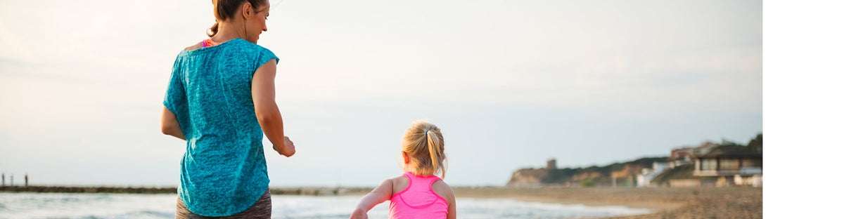 Mother and daughter running on beach