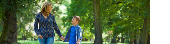 Mom holding son's hand while walking in the park
