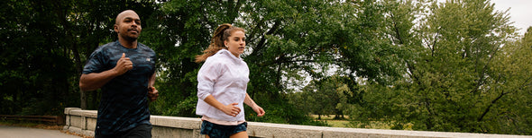 Man and woman running in park in New Balance gear