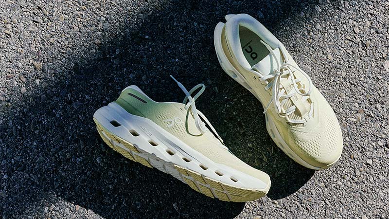 Pair of light-colored On Cloudrunner 3 running shoes on a dark asphalt surface