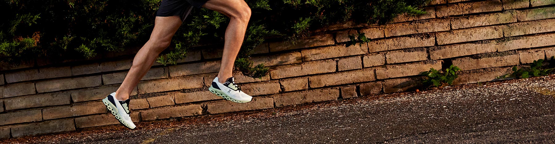 A man running in On Cloudstratus running shoes on a sidewalk lined with bricks.