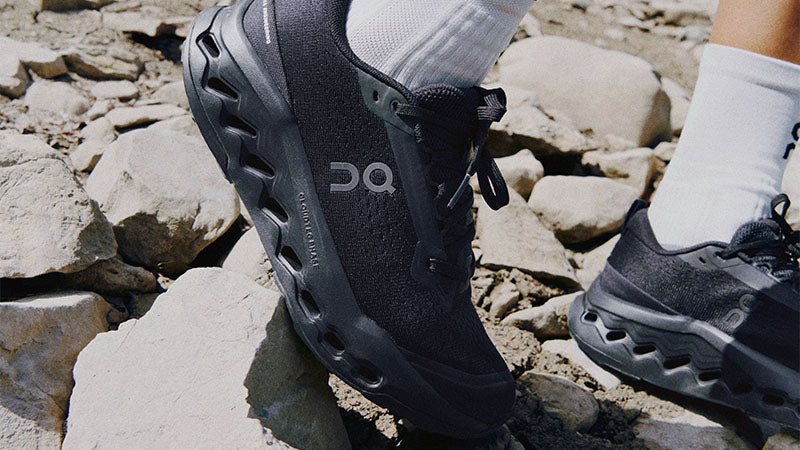 Closeup of a person on a rocky trail wearing black On Cloudsurfer Trail 2 trail running shoes