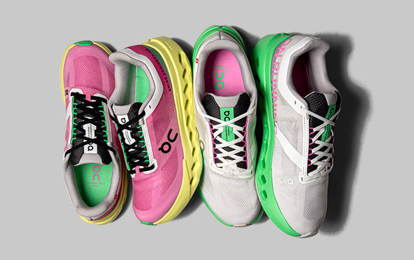 Closeup of a person standing on a platform in On Cloud 5 All White running shoes against a dark background.