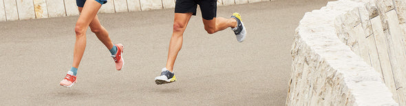 Woman and man running outdoors wearing On Running athletic apparel