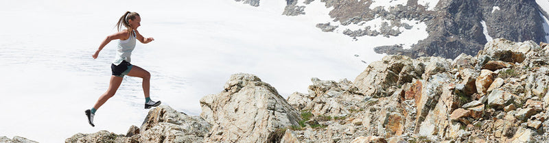 Woman running in On Running apparel in front of mountains