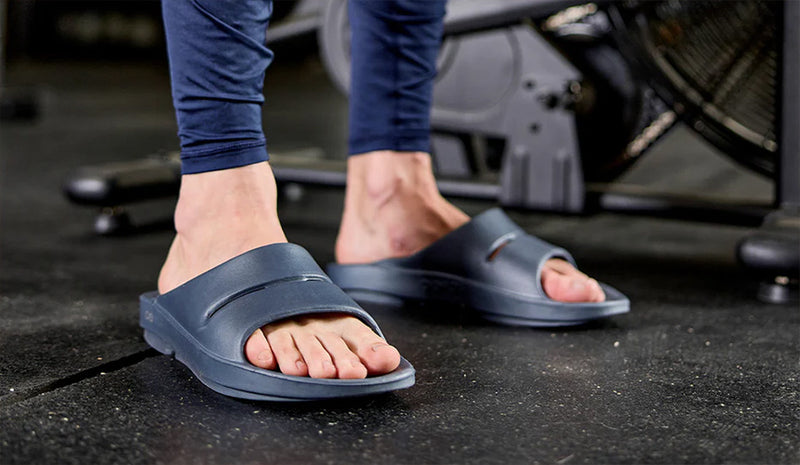 man wearing oofos ooahh slides in gym
