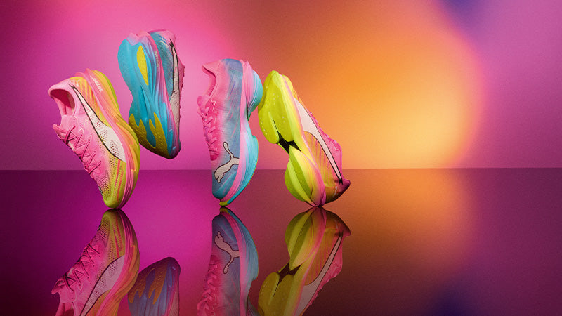 Stylized image of bright, colorful Puma running shoes on a reflective surface against a pink and orange gradient background