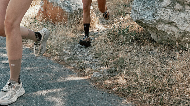 Two runners on an off-road trail wearing Salomon Aero Glide 4 GRVL running shoes.