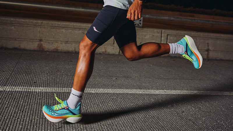 Man running on paved road in HOKA running shoes.