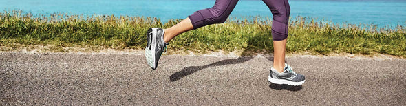 Woman running by ocean in Saucony running shoes