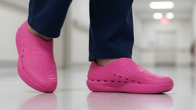 Closeup of a healthcare professional wearing pink Stand+ walking shoes and dark blue scrubs