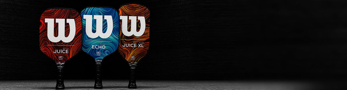 Wilson Juice, Echo and Juice XL Energy Pickleball Paddles displayed standing on a gray floor against a dark black background.