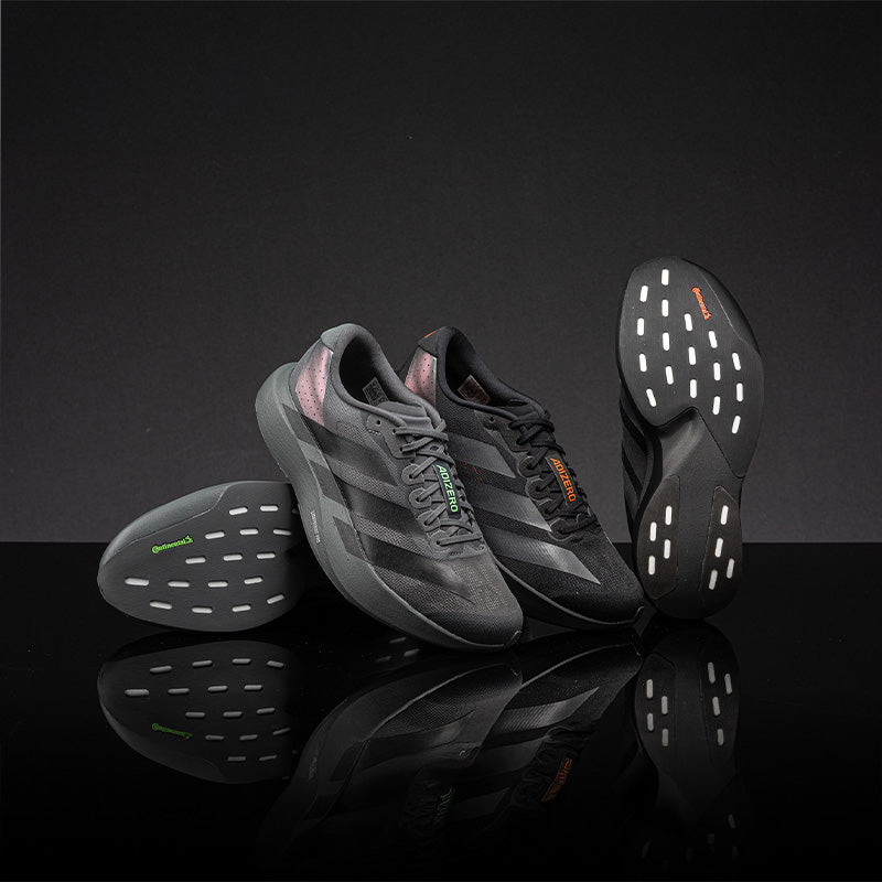 Gray adidas adiZero EVO SL running shoes on a reflective black surface and dark background
