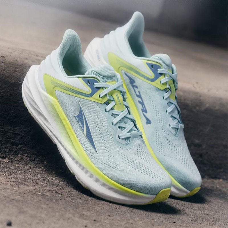 Light blue and yellow women's Altra Torin 9 running shoes on a concrete curb