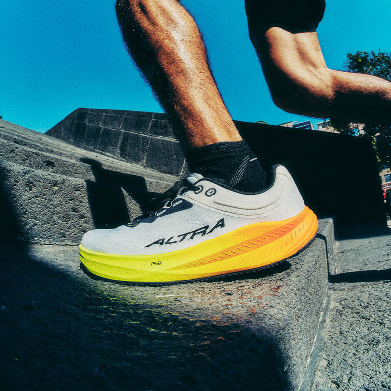 A person running up concrete stairs wearing Altra Torin 9 running shoes