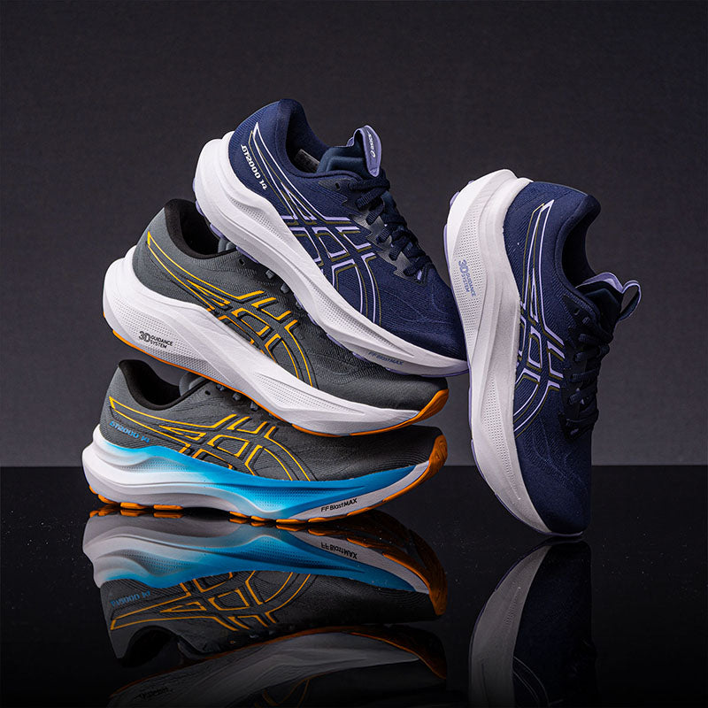 two pairs of ASICS GT-2000 14 running shoes stacked and posed together on reflective surface and a dark gray background
