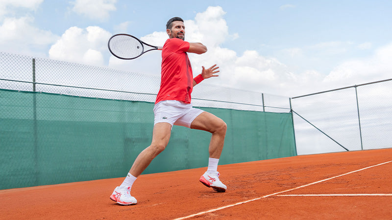 Tennis pro Novak Djokovic playing on a clay court in ASICS shoes