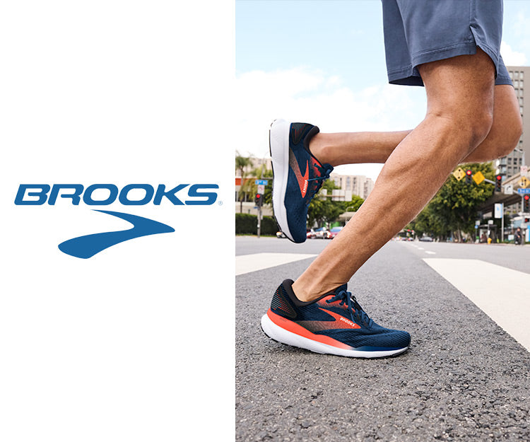 A man running down a city street with buildings in the background, wearing the Brooks Ghost 16 running shoes.