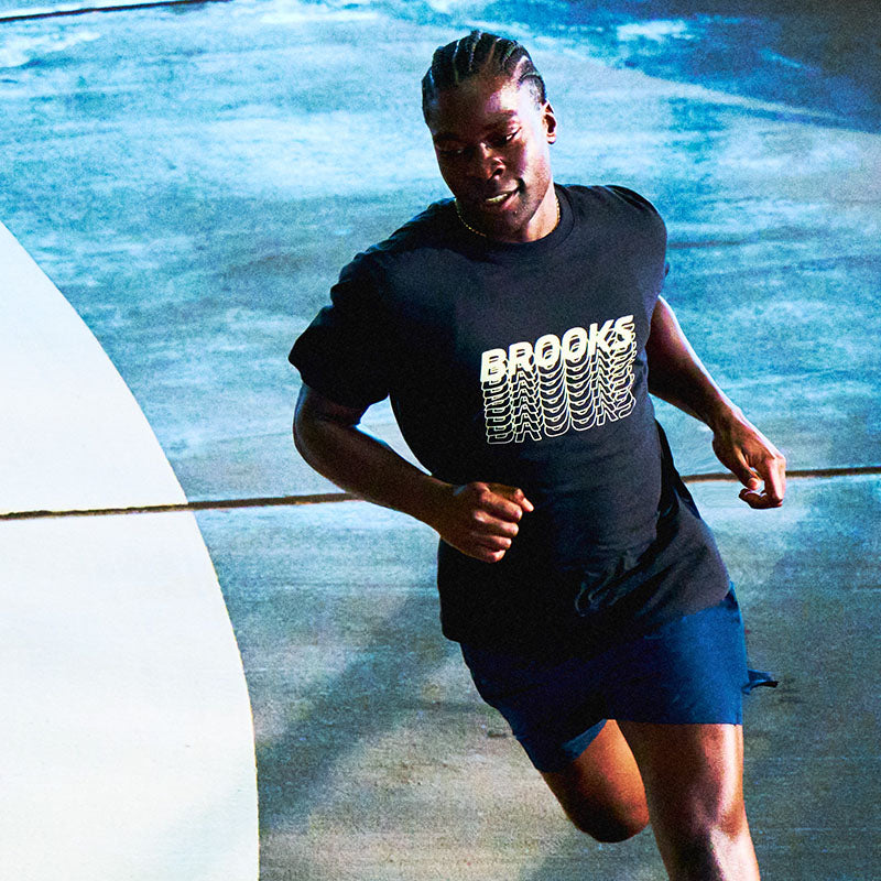 A person running on a paved surface wearing a black 'Brooks' t-shirt