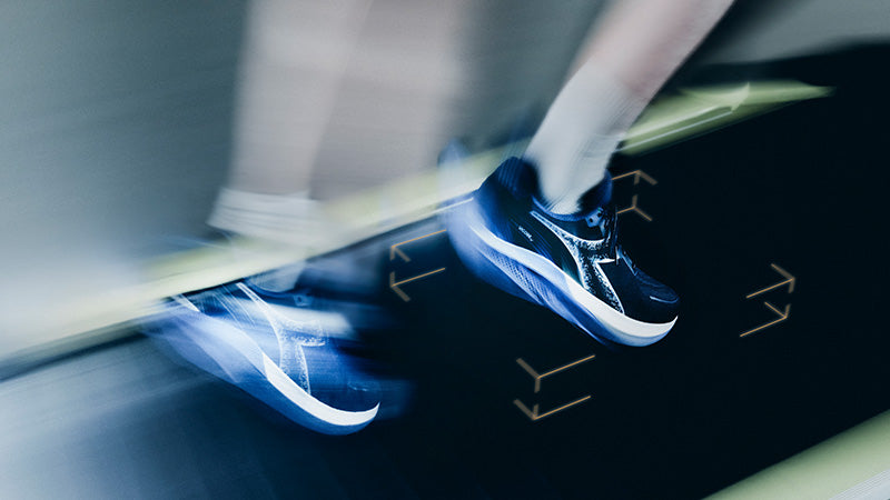 Person wearing blue Diadora running shoes stepping onto a black platform with a blurred background