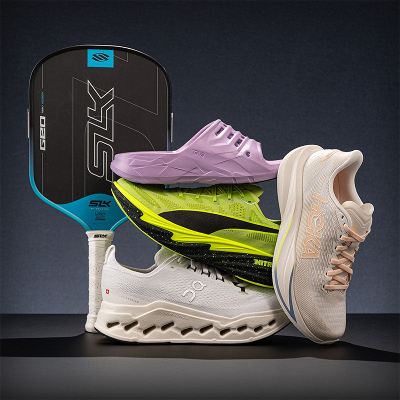 A collection of four athletic shoes from the brands Teva, HOKA, Puma and On, plus a Selkirk pickleball paddles posed in a dark studio setting.
