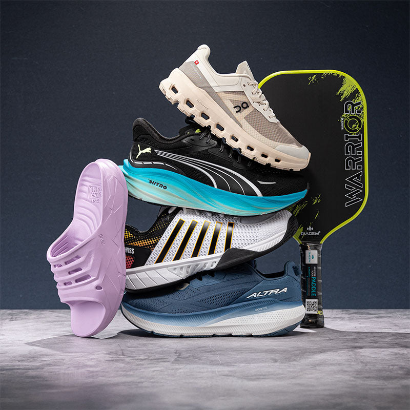 Stack of athletic shoes with a pickleball paddle on a dark background