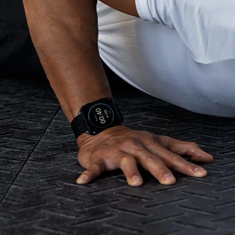 Person doing pushups while wearing a black Garmin Venu X1 Premium GPS Sportwatch on a black gym floor