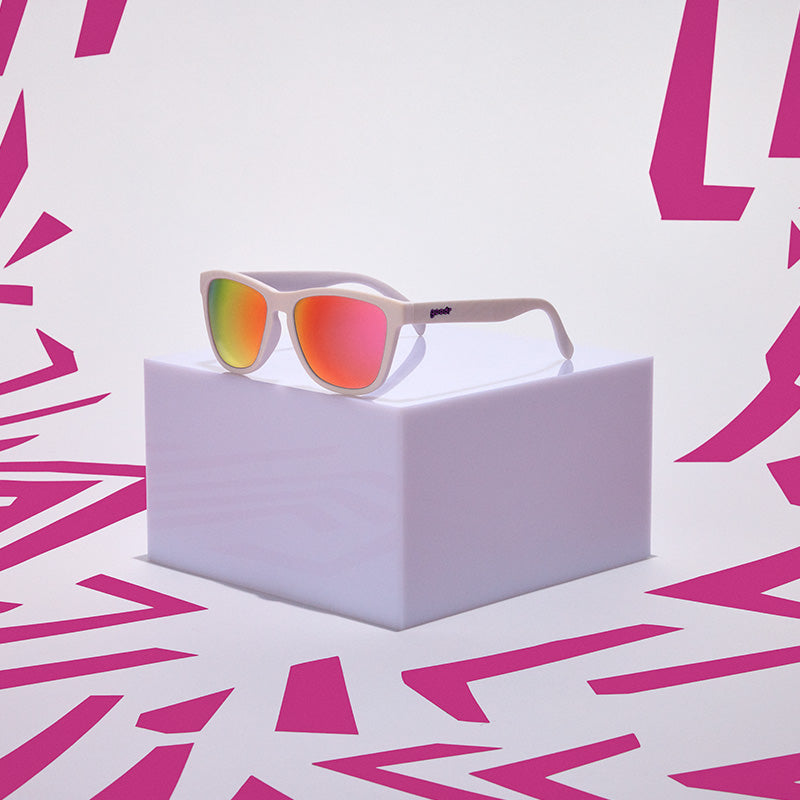 goodr OG Neon is My Neutral Sunglasses with red-tinted lenses on a white box against a pink geometric pattern