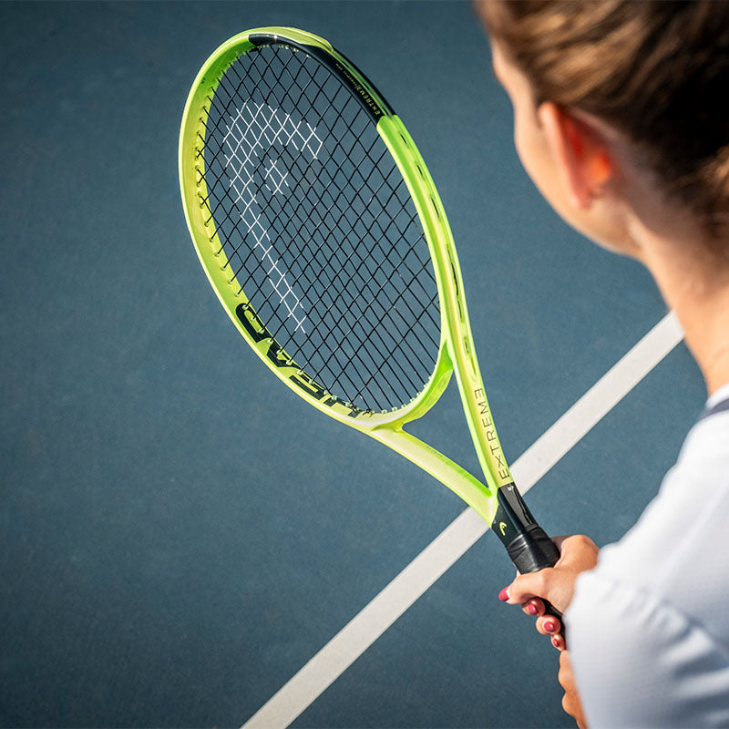 over-the-shoulder view of a tennis player holding a HEAD Extreme 2026 tennis racquet over a blue tennis court