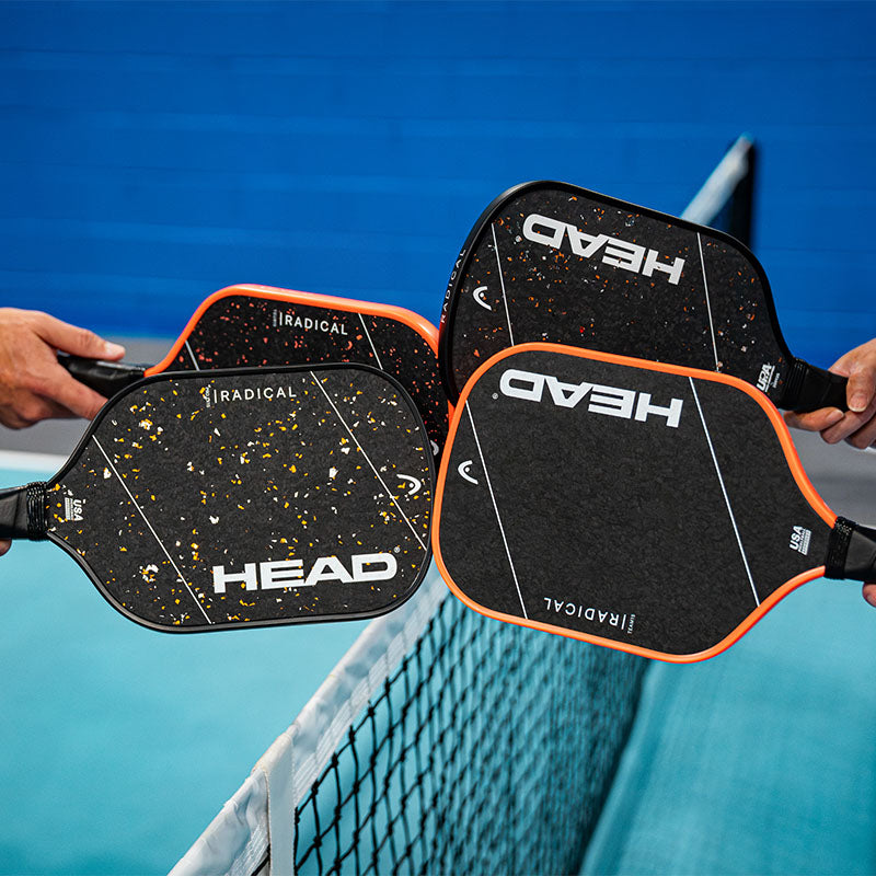 Four HEAD Radical pickleball paddles held by people on a pickleball court with a blue background.