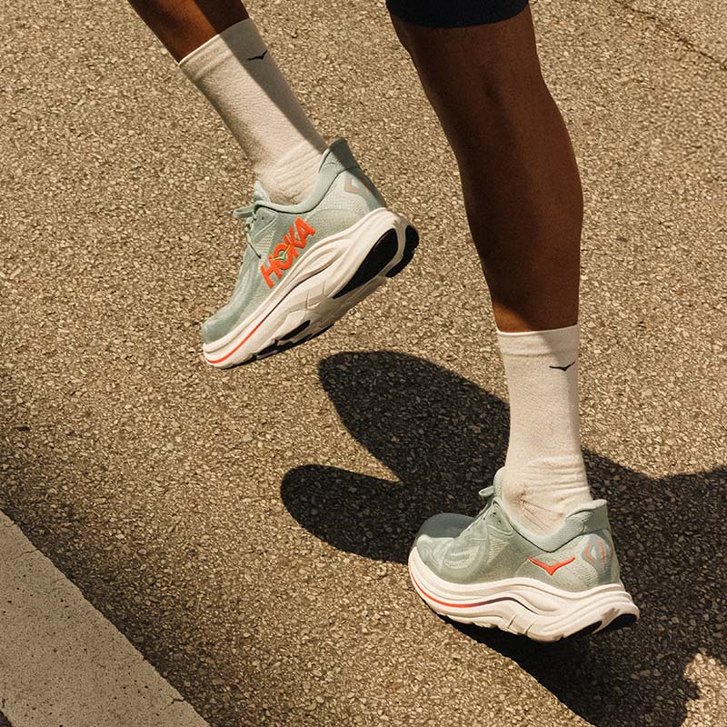 close-up of a person running in HOKA Clifton 10 running shoes on a paved surface