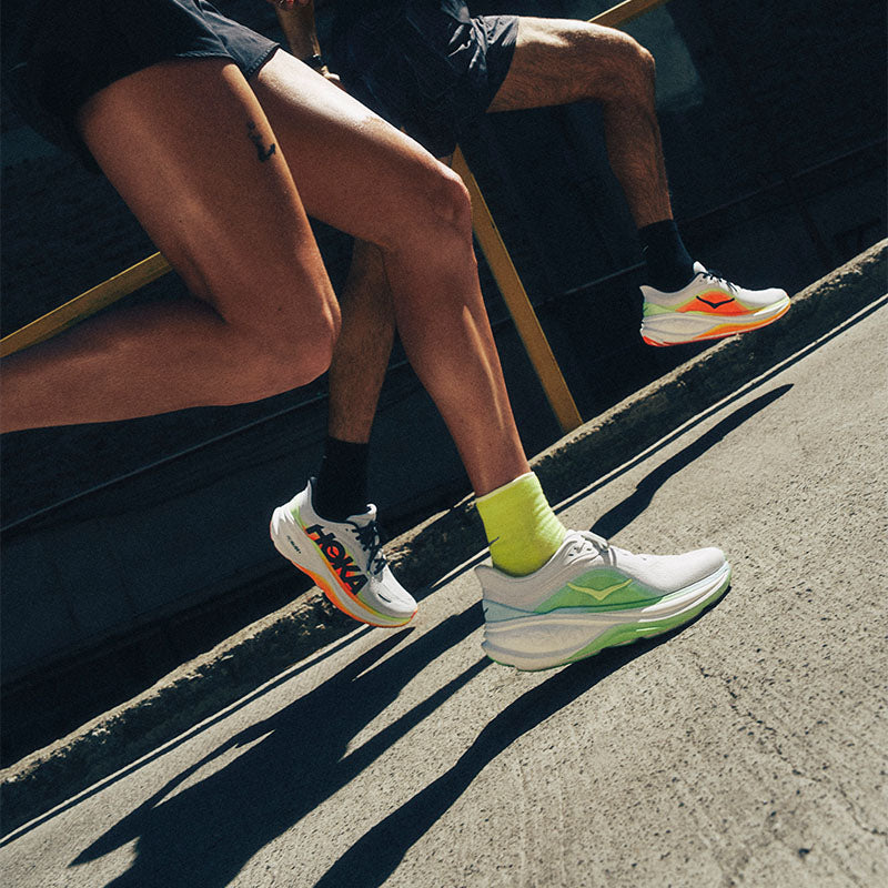 Runners in action on a paved street wearing HOKA Clifton Pro running shoes