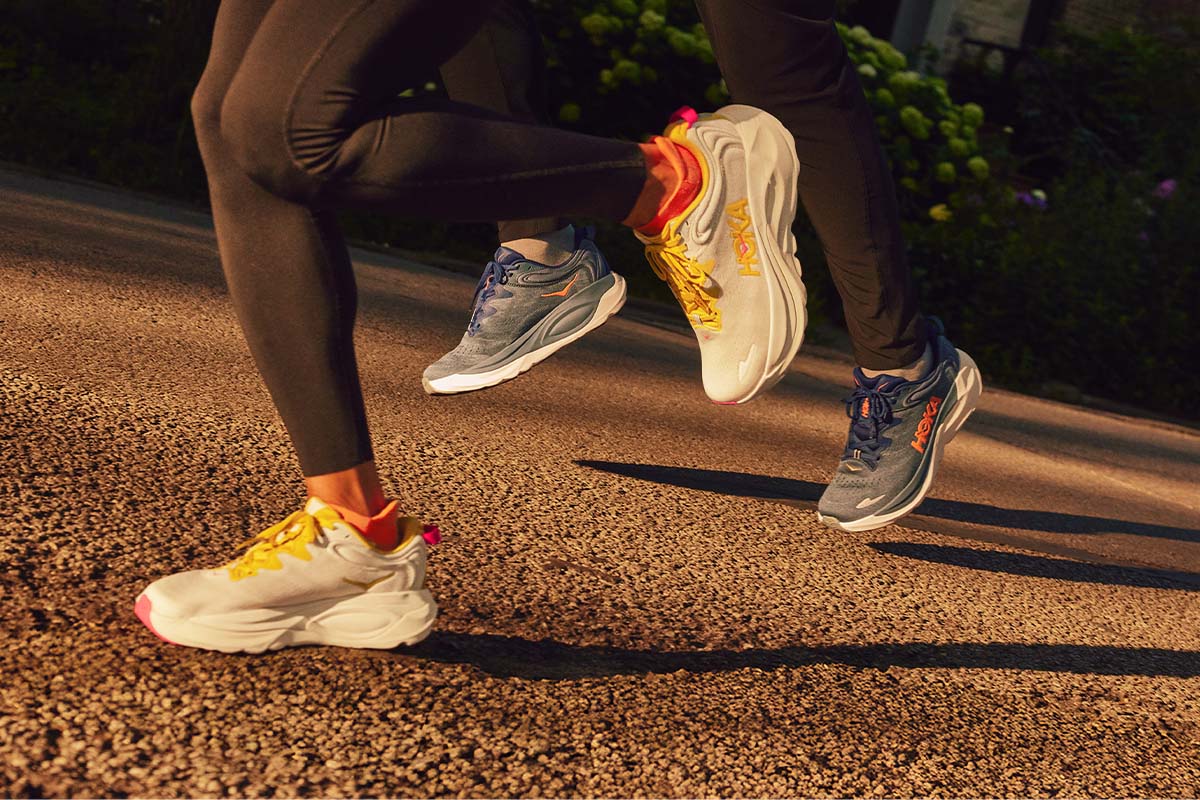 Two people in HOKA running shoes on a road with a blurred background