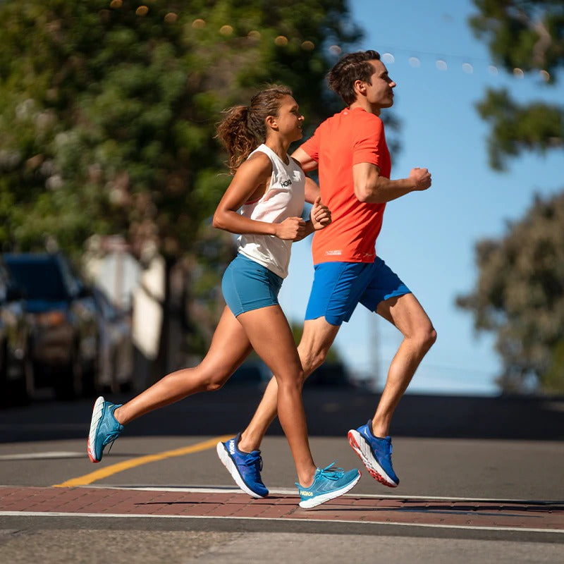 man and women running with blue hoka shoes on road