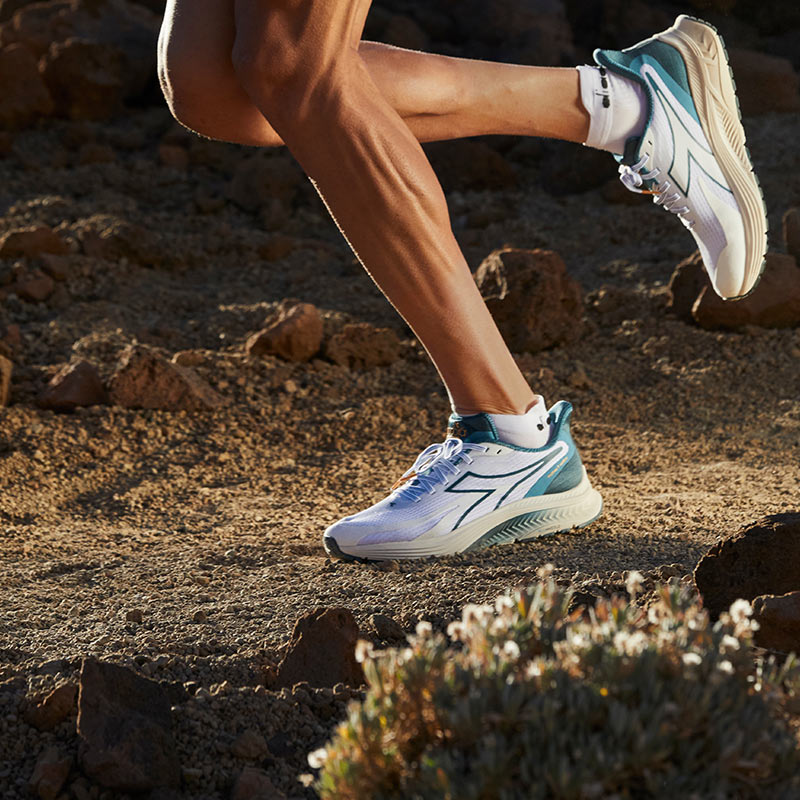Lifestyle image: a person running a gravel trail in Diadora running shoes