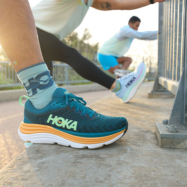 Men and women stretching their legs in HOKA Gaviota 5 running shoes.