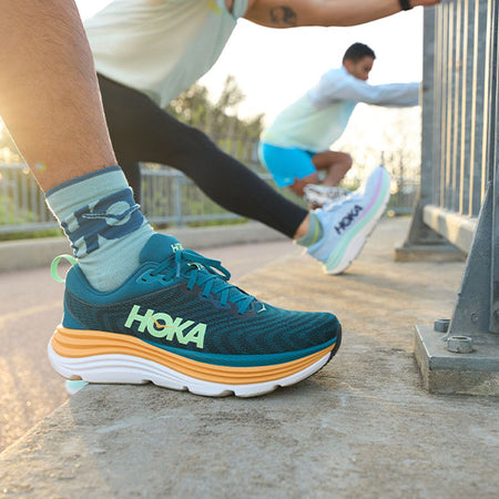 Men and women stretching their legs in HOKA Gaviota 5 running shoes.