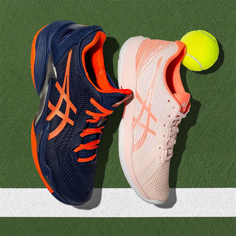 Men's and women's ASICS tennis shoes on a green tennis court.