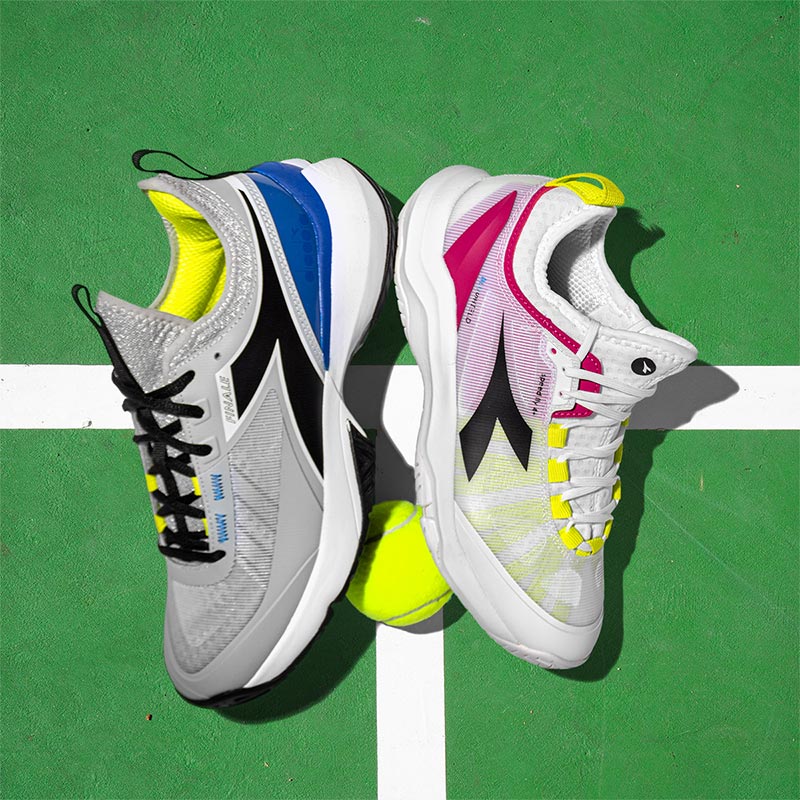 Men's and women's Diadora tennis shoes on a green tennis court.