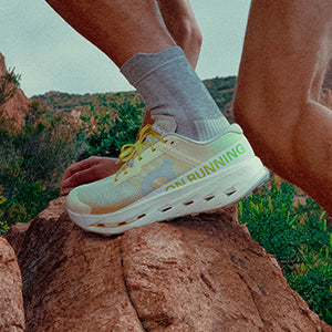 Person wearing On Cloudultra Pro trail running shoes on a rocky surface with a natural landscape in the background