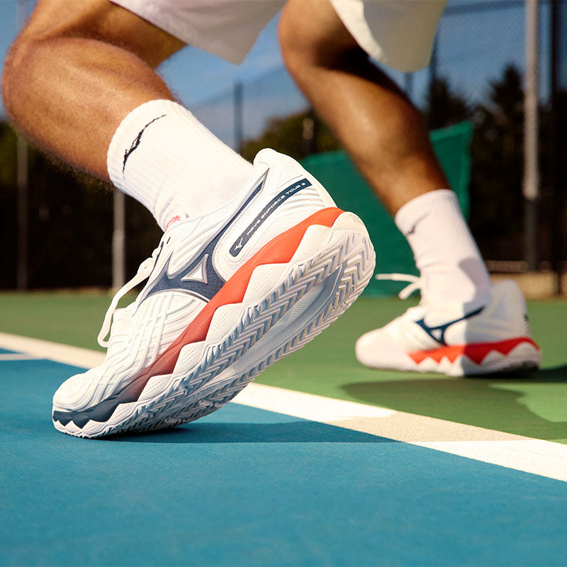 a tennis player on a blue and green court wearing Mizuno Wave Enforce Tour 2 shoes