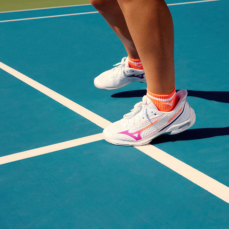 a tennis player on a blue court wearing Mizuno Wave Exceed Tour 7 women's tennis shoes