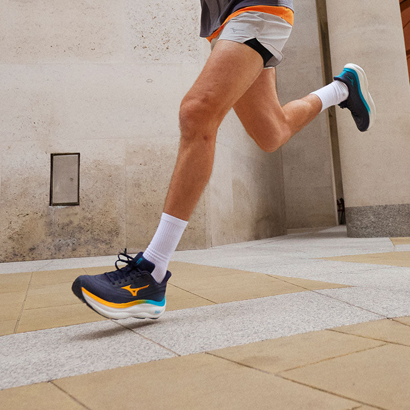 Person running in Mizuno Wave Sky 9 running shoes on stone pavement