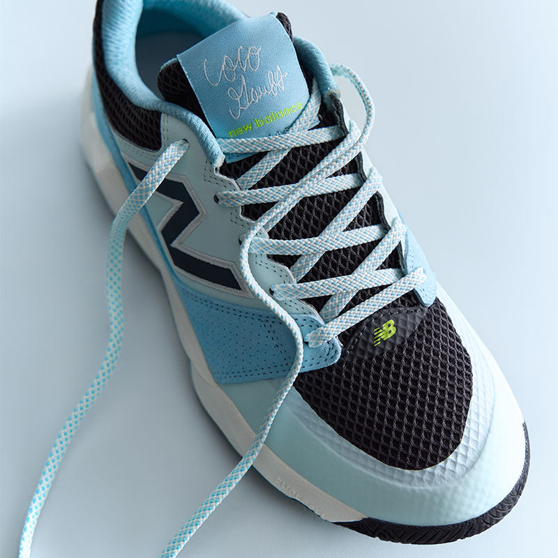 Light blue and black New Balance Coco Delray tennis shoe on a light blue background