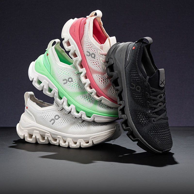 Four On Cloud X Tempo training shoes stacked together on a dark studio surface against a dark background. The shoes include white, mint green, coral pink, and dark gray/black colorways, all showing the brand's chunky wavy sole and mesh upper design.