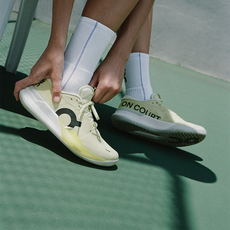 Person wearing light-colored On The Roger Pro 3 tennis shoes on a green tennis court surface